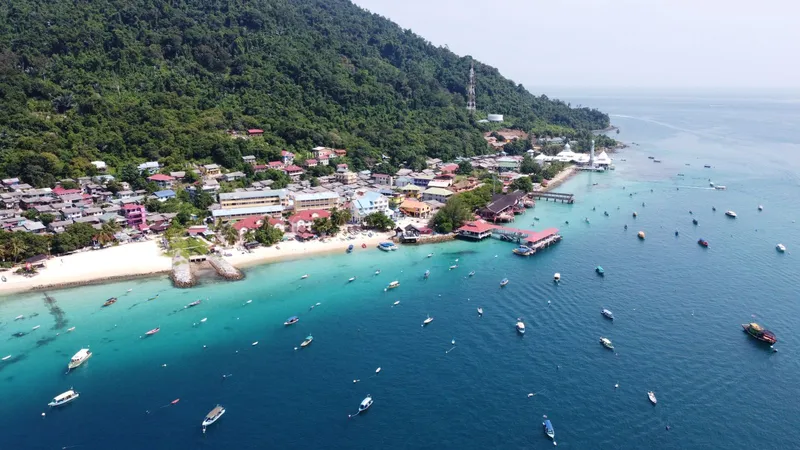 Aerial view of a fishing village on a turquoise coast under a clear sky