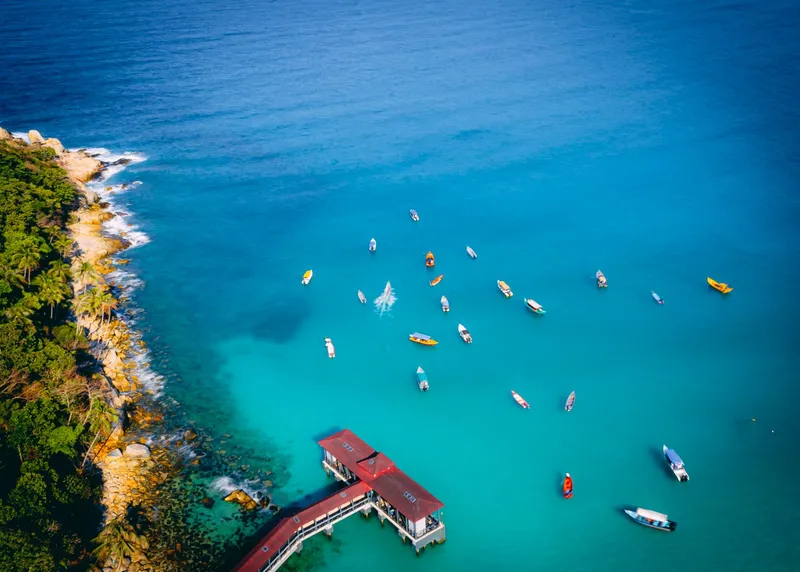 Aerial view of boats on turquoise water next to a pier
