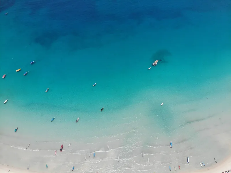 Drone view of boats on clear turquoise water near a coast